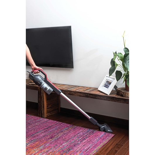 BLACKDECKER AVT12 cordless stick vacuum cleaner being used on purple rug in living room.