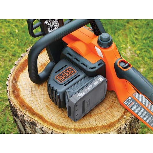 BLACK+DECKER BCCS1020D1 chainsaw with battery on tree stump outdoors.