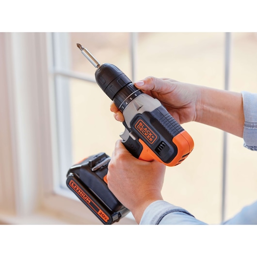 BLACK+DECKER cordless drill BCD70250PK with orange and black design, 20V lithium battery, held in hands indoors.