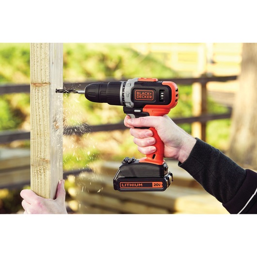 BLACK+DECKER BCK21S1S cordless drill 20V in use, drilling into wood, outdoor setting.