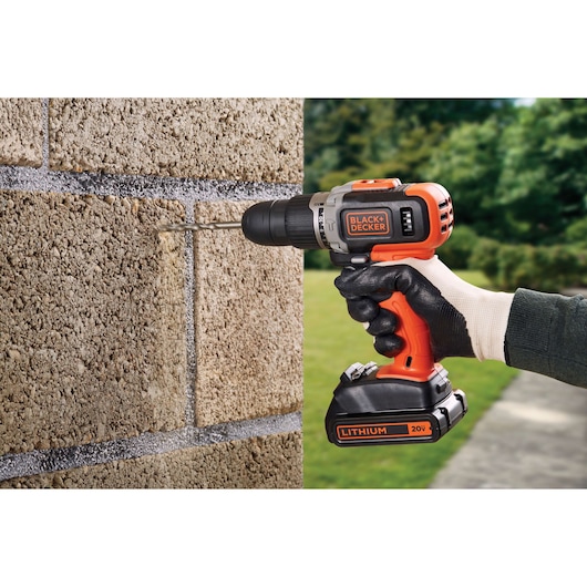 BLACKDECKER BCK21S1S cordless drill with 20V lithium battery drilling into masonry, close-up side view.