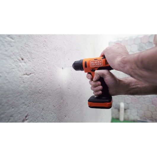 BLACKDECKER BCD712VHD cordless drill in use against a textured wall, close-up side angle.