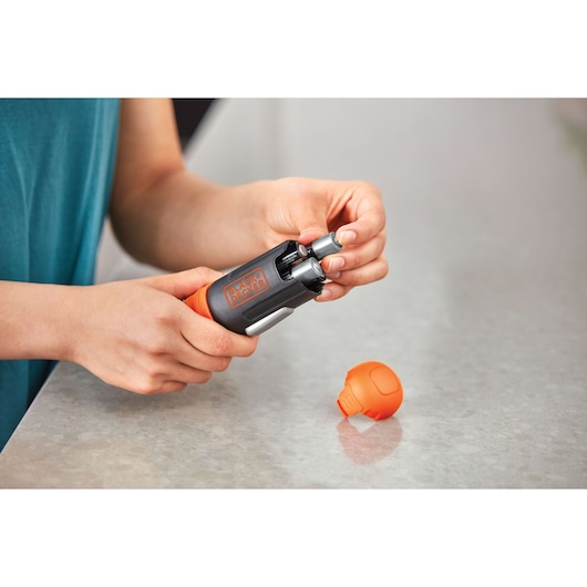 Photo of BLACK+DECKER BCF601AA compact screwdriver with orange cap removed, shown in hand on a gray countertop.