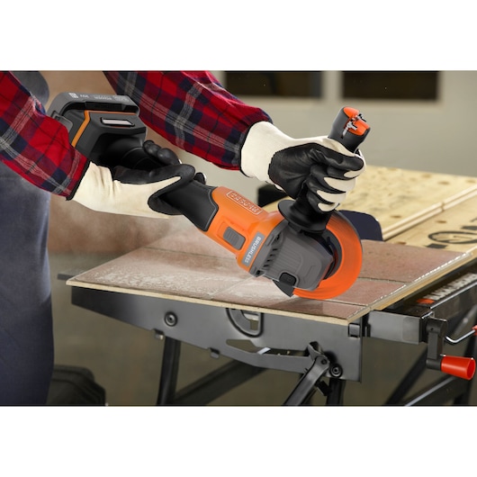 Photo of BLACKDECKER BCG6L8B cordless angle grinder with orange accents cutting tile on a workbench.