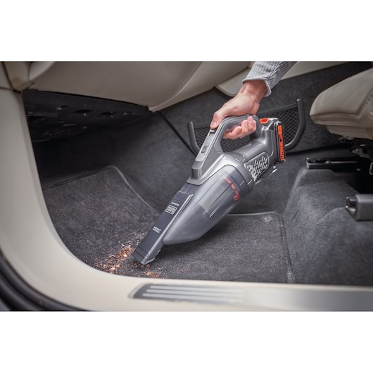 BLACKDECKER BCHV001D1E handheld vacuum cleaner used to clean car floor mat, angled side view.