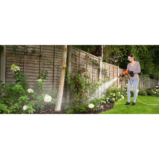 Photo of BLACKDECKER BCPW350E1 pressure washer spraying water on garden plants outdoors.