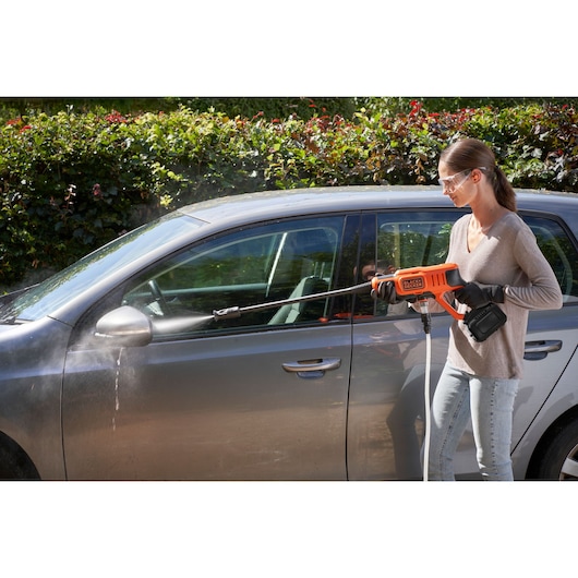 BLACKDECKER BCPW350E1 cordless pressure washer cleaning a gray car outdoors.