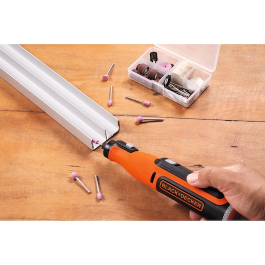 BLACKDECKER BCRT8K35 rotary tool kit, orange and black, with accessories, in use on metal profile, side angle