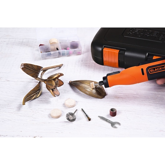 BLACKDECKER BCRT8K35 rotary tool kit with accessories, polishing a metal decoration, flat lay angle.