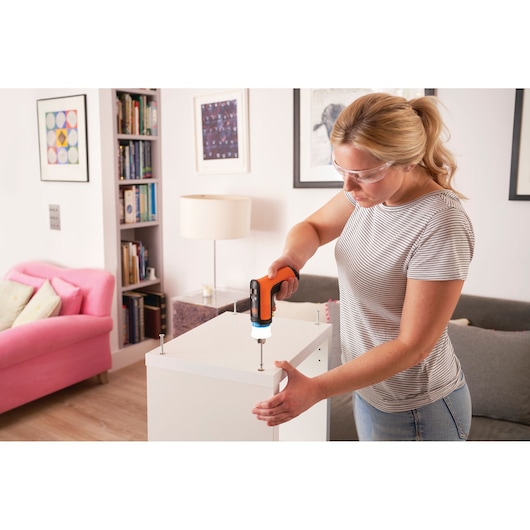 BLACKDECKER BCRTA601I cordless screwdriver used to assemble a white cabinet in a living room setting.