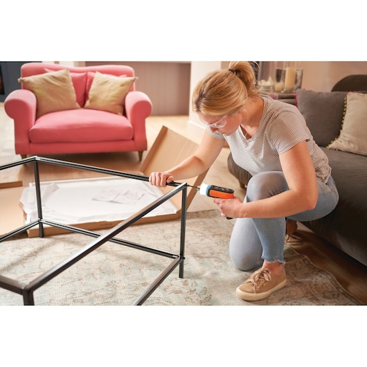 BLACKDECKER cordless screwdriver BCRTA601I used to assemble a metal table frame in a living room setting.