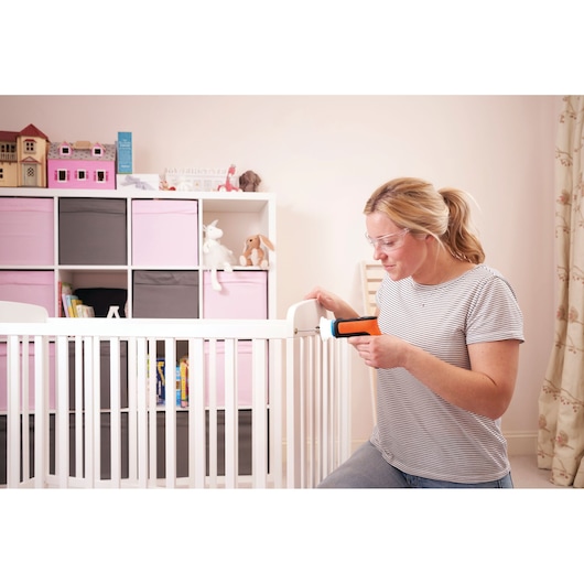 BLACKDECKER BCRTA601I cordless screwdriver used to assemble a white crib in a nursery setting.