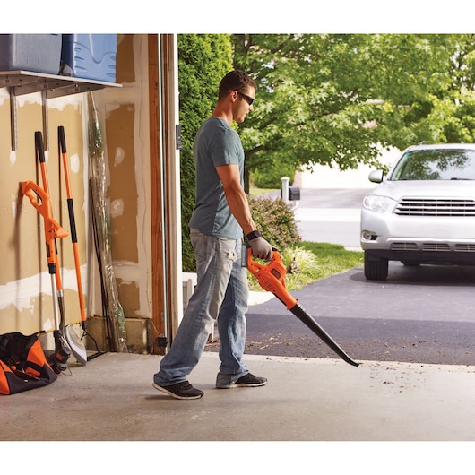 BLACKDECKER BCSW221E1 leaf blower used in a garage, bright orange color, man cleaning driveway.
