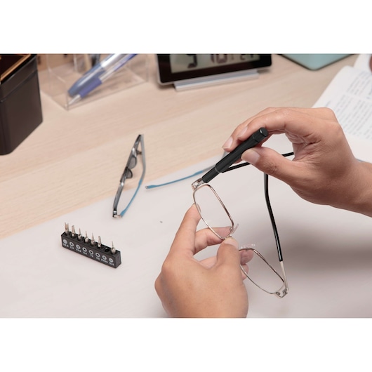 BLACKDECKER BD40K27 precision screwdriver used to repair eyeglasses, bit set visible on desk in home environment.