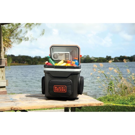 BLACK+DECKER BDC24L portable cooler filled with drinks and snacks shown outdoors by a lake.