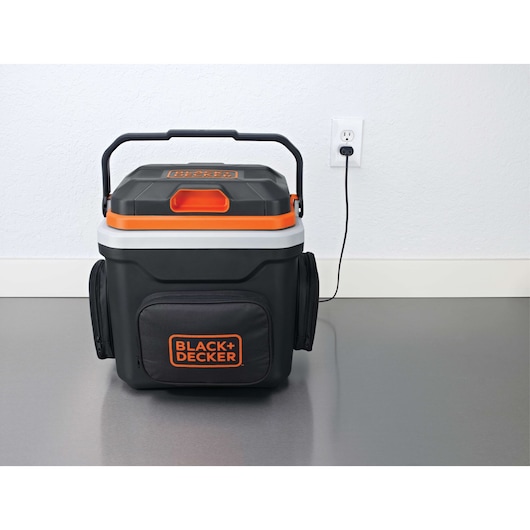Front angle photo of BLACKDECKER portable cooler BDC24L, black with orange accents, plugged into wall outlet.