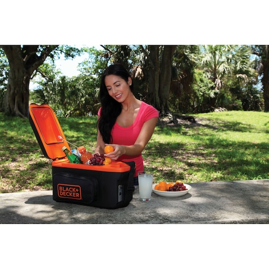 Photo of BLACK+DECKER BDC8-LA portable cooler on picnic table outdoors, open and filled with drinks and fruit.