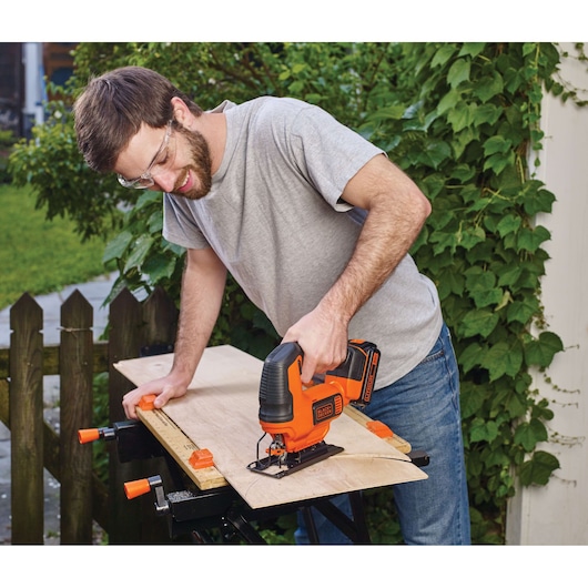 Photo of BLACKDECKER BCK22S1S cordless jigsaw cutting plywood outdoors on a workbench.