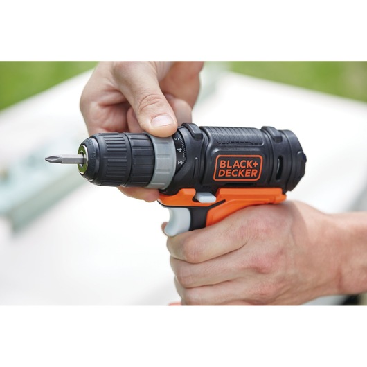 Close-up of a person adjusting the settings on a BLACK+DECKER cordless drill screwdriver.