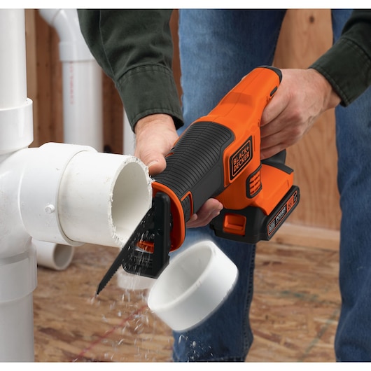 Photo of BLACK+DECKER BDCR20C reciprocating saw cutting white PVC pipe indoors.