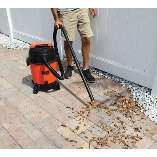 BLACKDECKER BDWD15 wet and dry vacuum being used to clean leaves from outdoor patio.