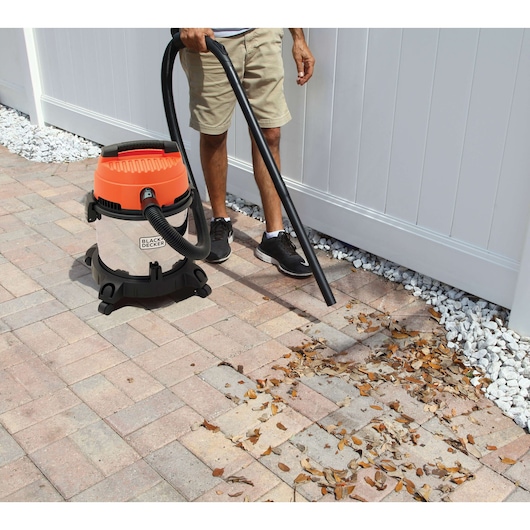 Photo of BLACKDECKER BDWDS20 wet dry vacuum being used outdoors on patio to clean leaves.