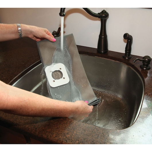 BLACKDECKER BDWDS20 vacuum filter being rinsed under faucet in kitchen sink.