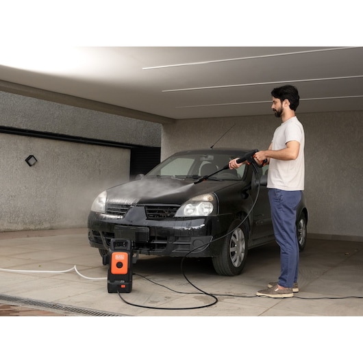 BLACKDECKER BEPW1520 pressure washer used to clean black car in driveway.