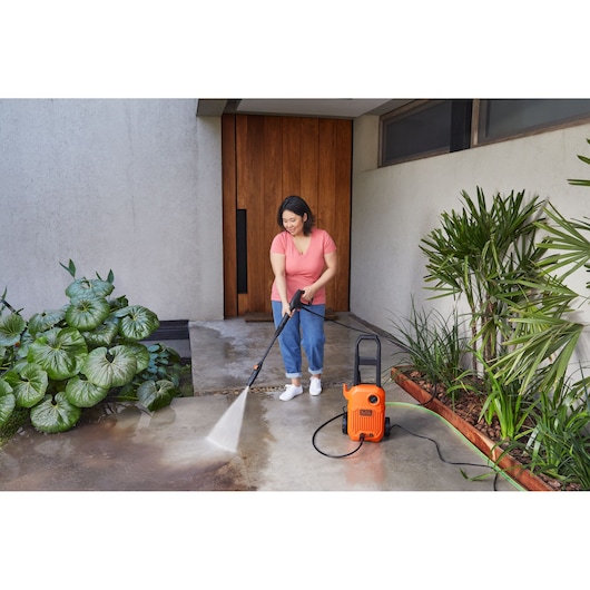 BLACKDECKER BEPW1600L pressure washer cleaning outdoor patio near plants.