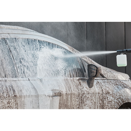 BLACKDECKER BEPW2200 pressure washer spraying foam on dirty car side, closeup, front side view.