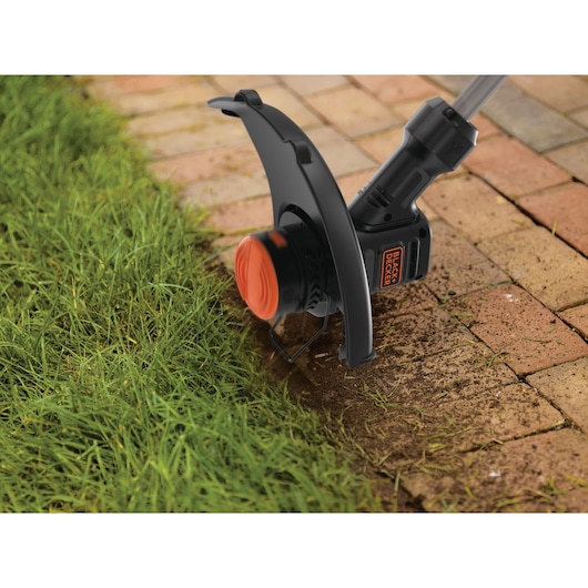 Photo of BLACKDECKER BEST935 string trimmer head edging lawn next to brick walkway.
