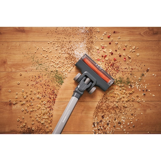 BLACKDECKER BHFEA18D1 cordless vacuum head cleaning assorted debris on wood floor, top view.