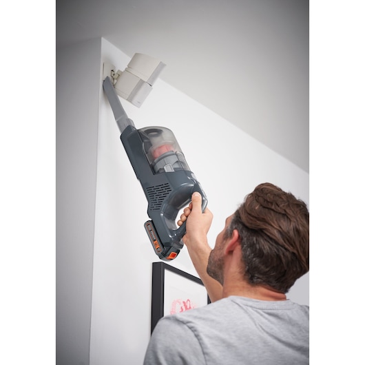 BLACKDECKER BHFEA18D1 cordless vacuum cleaner with extension nozzle cleaning ceiling corner.