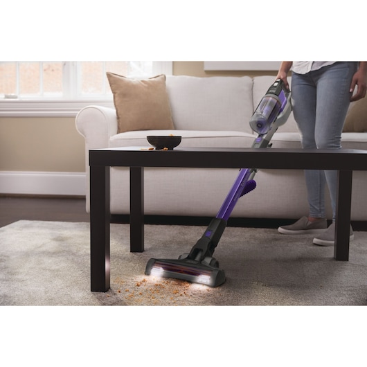 BLACKDECKER BSV20PET cordless stick vacuum cleaning crumbs on carpet near sofa and coffee table.