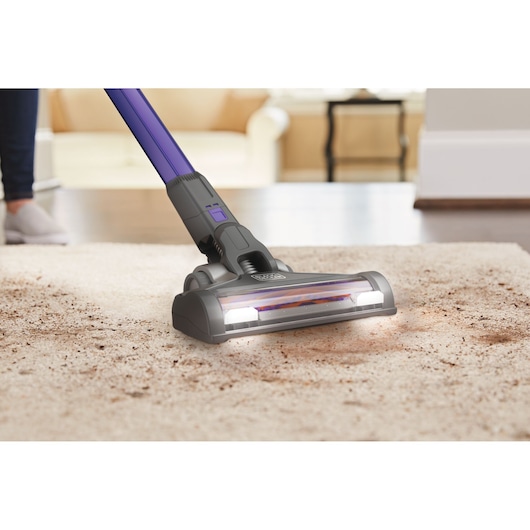 BLACKDECKER BSV20PET cordless vacuum cleaning dirt from carpet in a living room, close-up of vacuum head.