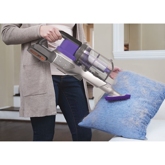 BLACKDECKER BSV20PET cordless vacuum cleaning pet hair from blue pillow in living room