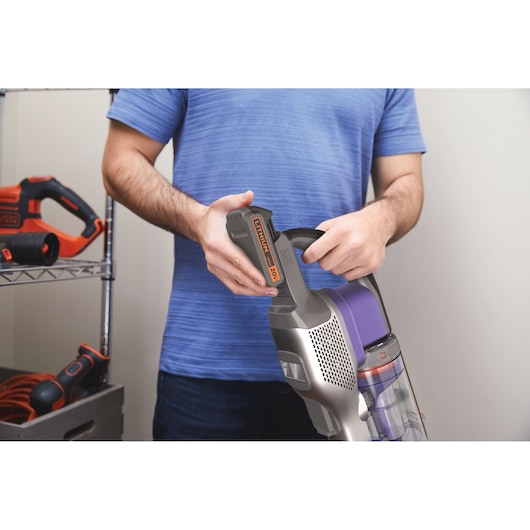 BLACKDECKER BSV20PET cordless vacuum being held, showing battery removal feature.
