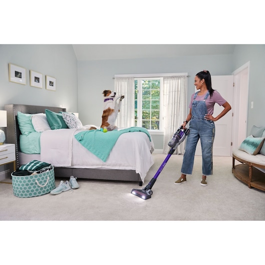 BLACKDECKER BSV20PET cordless stick vacuum cleaner in use in a bedroom, upright angle.