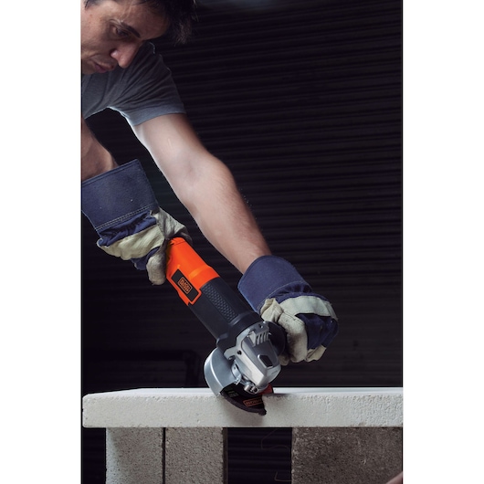 BLACKDECKER G720 angle grinder cutting concrete, operator wearing gloves and safety gear.