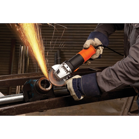 Photo of BLACKDECKER G720 angle grinder cutting metal pipe, sparks flying, operator wearing gloves.