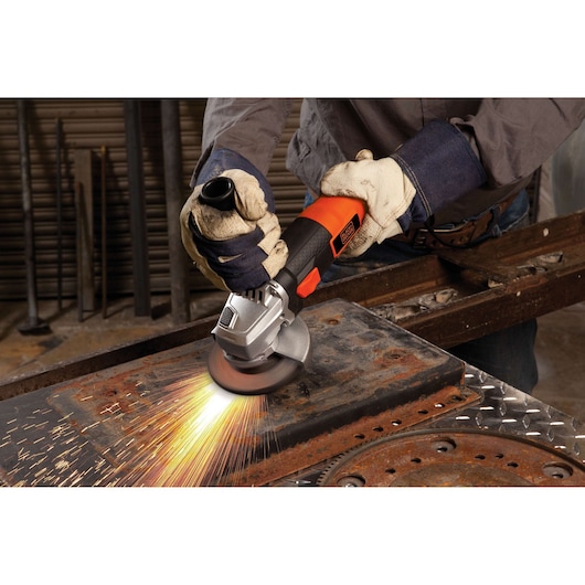 BLACKDECKER G720 angle grinder used on metal, sparks flying, worker wearing gloves in workshop.