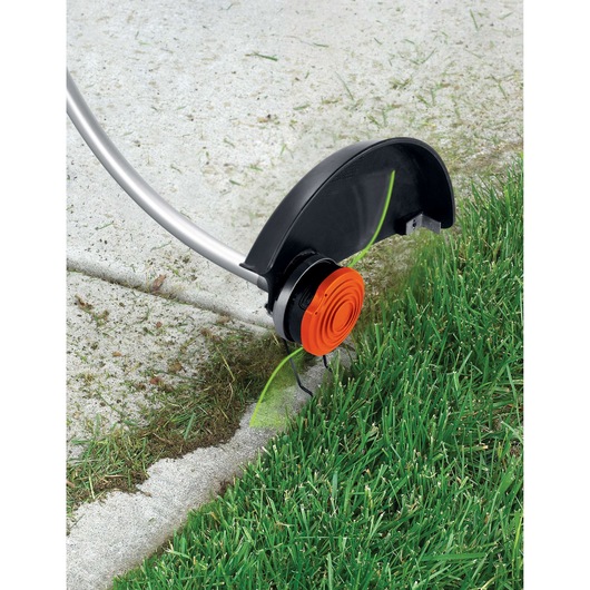 BLACKDECKER GH1100 string trimmer edging grass along concrete sidewalk, close-up view.