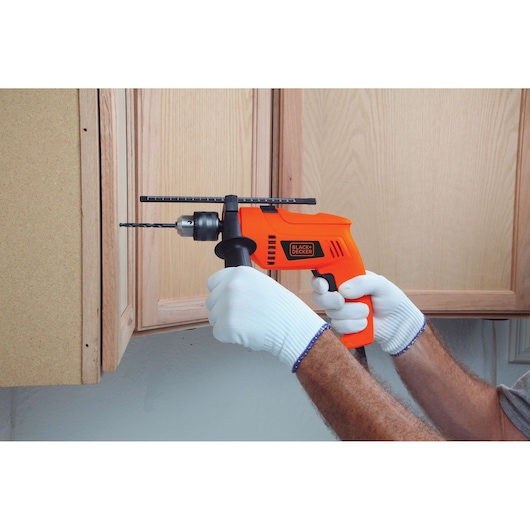 Photo of BLACKDECKER HD650 electric drill with side handle, used to drill into wooden cabinet.