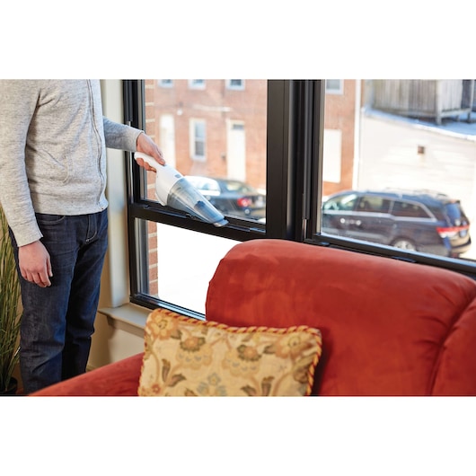 BLACKDECKER HNV220V12 handheld vacuum cleaning window sill in living room.