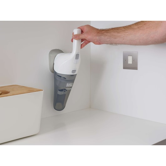 BLACKDECKER HNV220V12 handheld vacuum on wall charger, white and gray, being removed from mount.