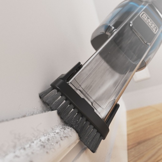 BLACKDECKER HNVD220J00 handheld vacuum cleaner with brush attachment cleaning a white surface, close-up angle.