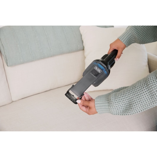 Photo of BLACKDECKER handheld vacuum HNVD220J00 being used on light-colored couch.