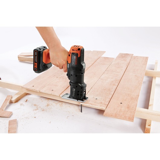 Photo of BLACKDECKER MTX20K3B cordless multi-tool cutting wood board, close-up of tool in use on white background.