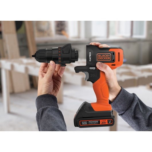 BLACK+DECKER MTX20K3B cordless drill with orange and black body, 20V battery, and detachable chuck held in hands.