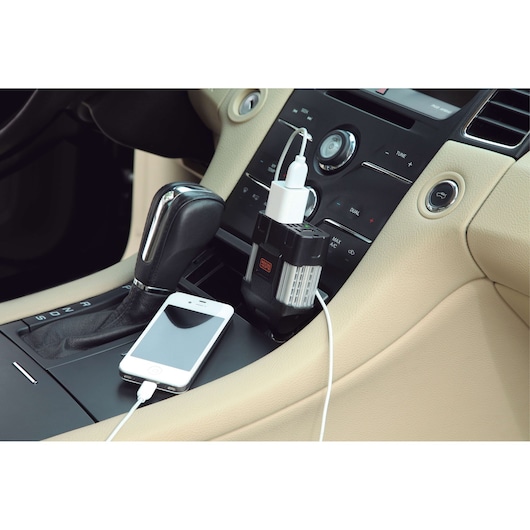 Photo of BLACKDECKER PI100LA power inverter plugged into car console, charging a smartphone with a USB cable.